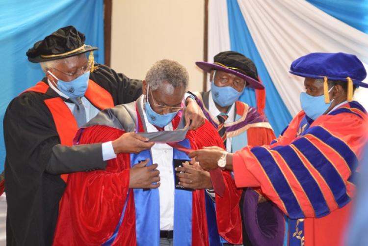 Members of the Senate assist VC dress in academic regalia